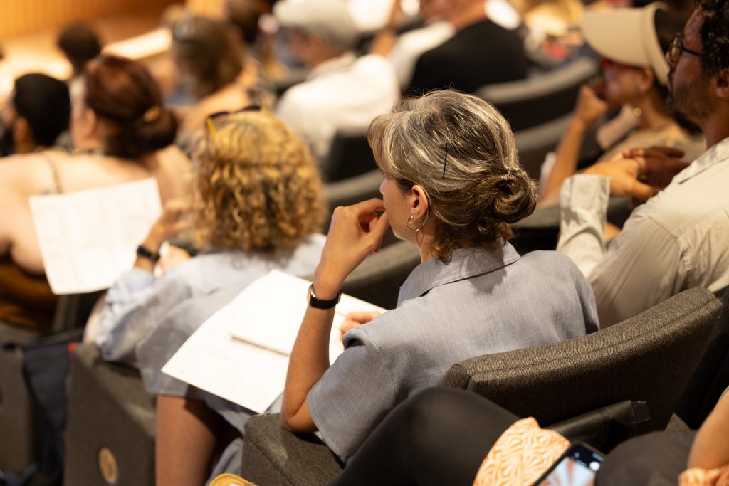 people sat in a lecture theatre holding paper on their lap